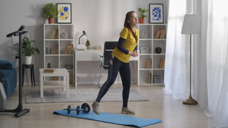 teen-girl-is-doing-aerobics-in-living-room-at-morning-stepping-and-lifting-leg-in-rhythm-of-music-funny-sport-exercise-healthy-lifestyle-of-youth