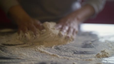 manos de mujer haciendo masa de pizza en una mesa de mármol llena de harina
