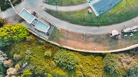 Drone-shot-flying-above-an-ancient-amphitheater,-huge-stage-with-giant-screen,-grass-and-seats,-golden-hour-Israel