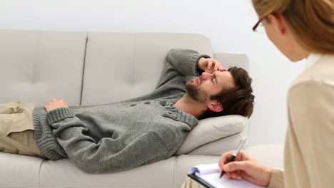 young man lying on sofa talking to his therapist