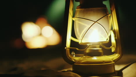 Kerosene-Lamp-Stands-On-The-Sand-In-The-Background-A-Fire-Tent