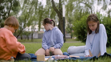 little girl with down syndrome doing crafts sitting in the park with her friends. she throws a piece of wood back