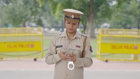 indian police officer checking handcuffs