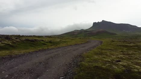 Low-aerial-fly-over-empty-dirt-road-in-rural-Iceland-nature