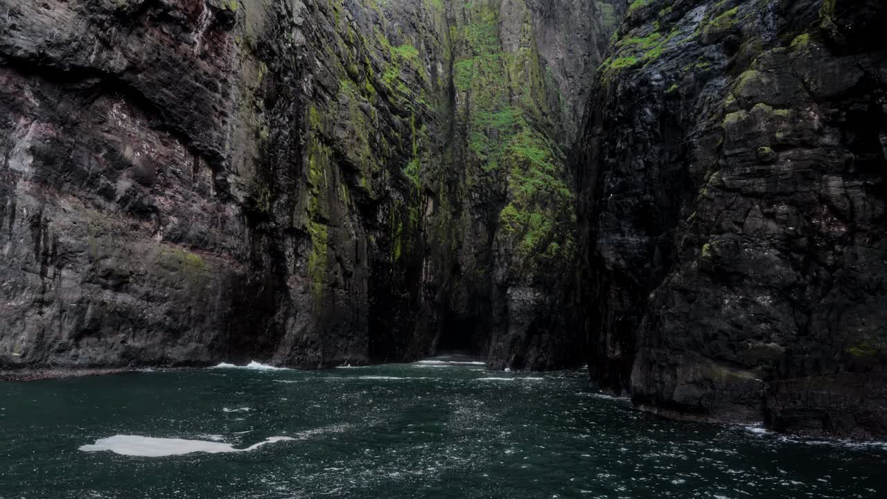 Majestic narrow sea canyon with moss-covered cliffs and deep emerald water