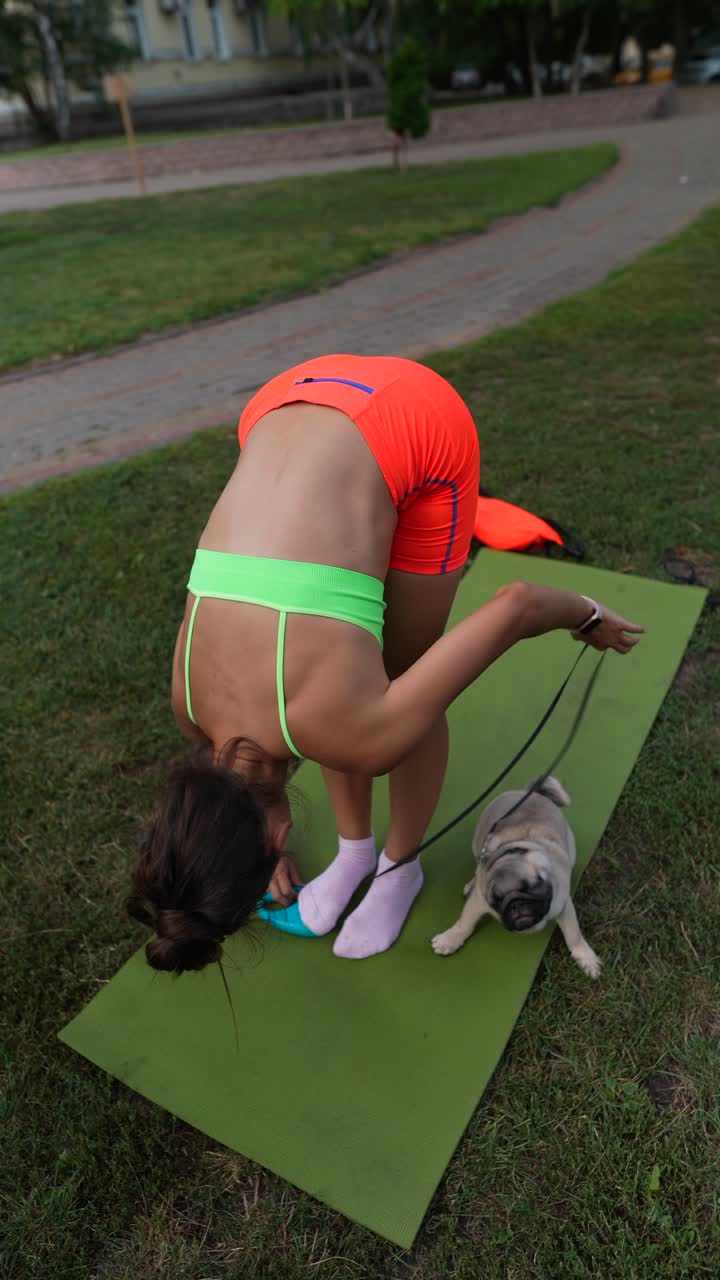 mujer haciendo yoga en un parque con su perro