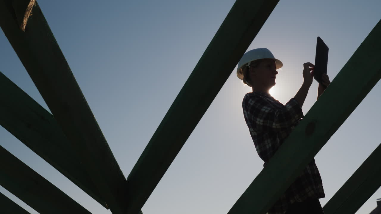 Female Architect Working With A Tablet On The Roof Of A Cottage