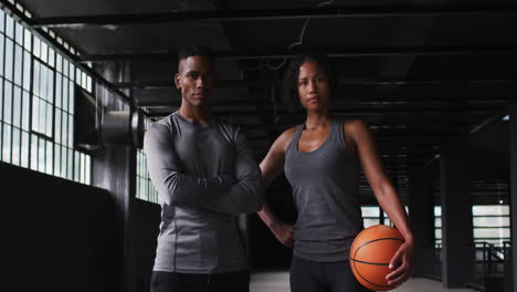 african american man and woman standing in an empty building holding a basketball