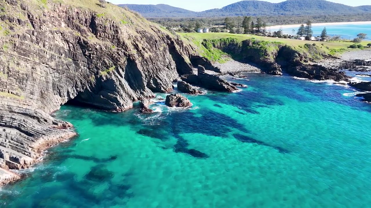 Ripresa aerea con drone di scogliere rocciose e acqua oceanica turchese limpida a Crescent Head, Australia