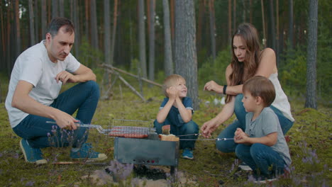 Ehepaar-Mit-Zwei-Kleinen-Söhnen-Ruht-Sich-Am-Wochenende-In-Der-Natur-Aus-Und-Grillt-Würstchen-Im-Familienpicknick-Im-Wald