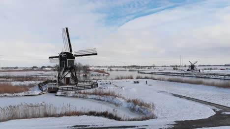 Aerial:-winter-snow,-traditional-Dutch-windmills-and-frozen-canal-polder-land