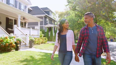 couple walking along suburban street holding hands