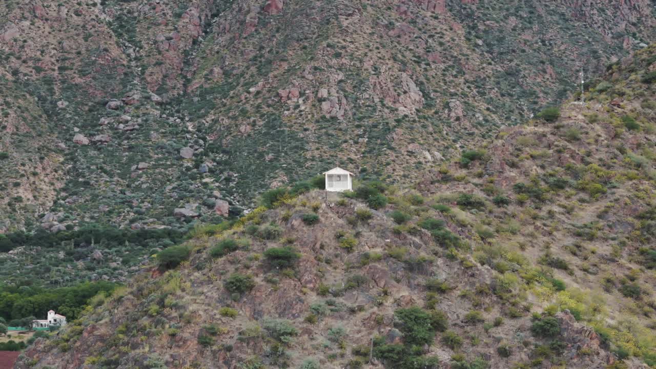 dron volando sobre la cima de la montaña capturando una casa religiosa blanca situada en la cima