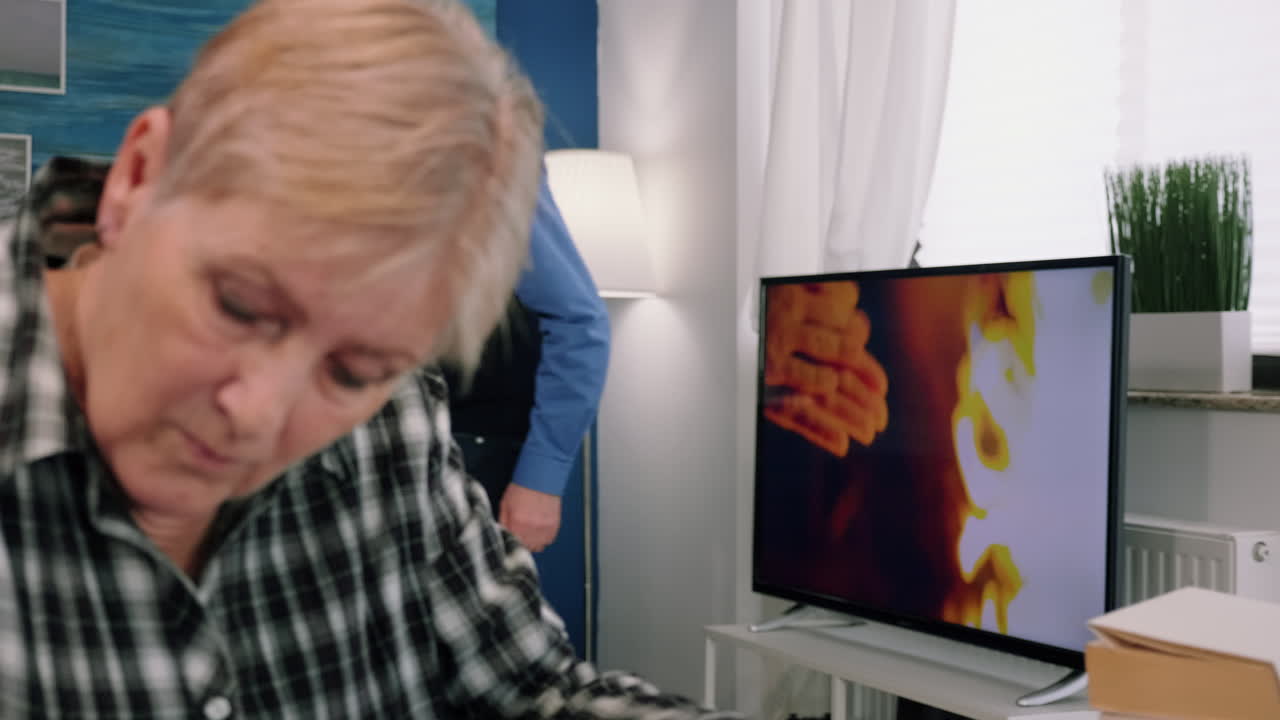 mujer elegante senior tomando notas en el cuaderno mientras usa la computadora portátil en casa