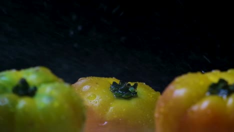 water drops splashing on fresh heirloom tomatoes against black backdrop