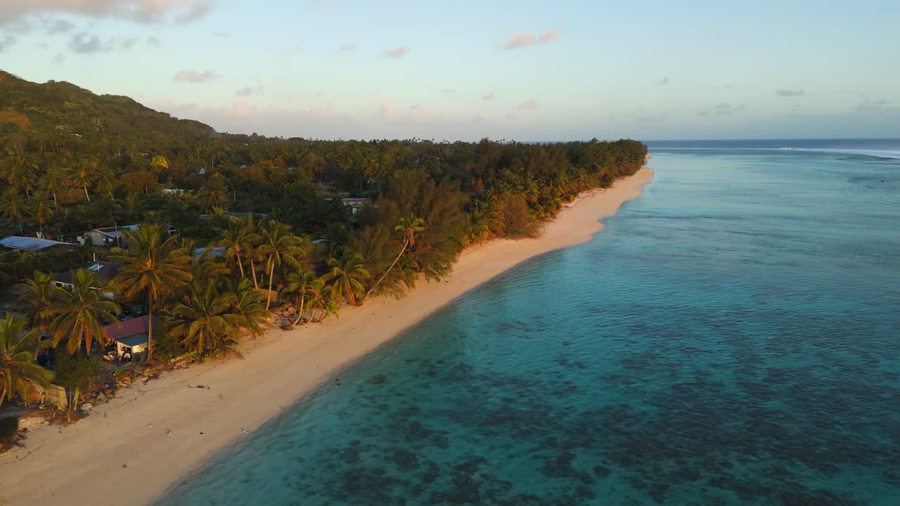 vista aérea de una playa tropical en rarotonga, islas cook, durante la puesta de sol, mostrando costas alineadas con palmeras, aguas turquesas, arrecifes de coral y vegetación exuberante