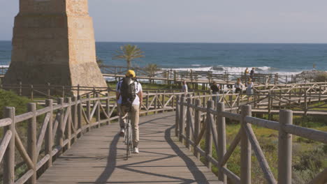 cyclist on a wooden path to the beach