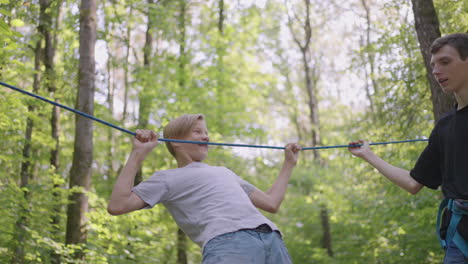 Small-boy-in-climbing-equipment-in-a-rope-Park.-Group-of-Caucasian-children-training-at-boot-camp.-In-the-children-camp-children-are-taught-to-overcome-obstacles-with-the-help-of-a-rope-crossing