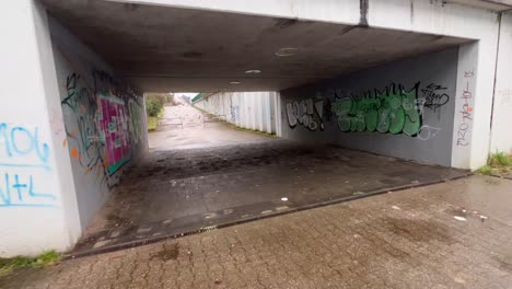 Dirty-spooky-wet-gloomy-underpass-in-Germany-with-graffitis-and-garbage-at-daytime