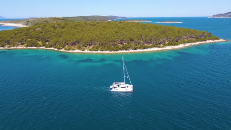 Yates-A-La-Deriva-En-La-Bahía-Cerca-De-La-Ciudad-Costera-De-Croacia-Contra-El-Telón-De-Fondo-De-Cielos-Azules-Y-Agua-Azul-Transparente