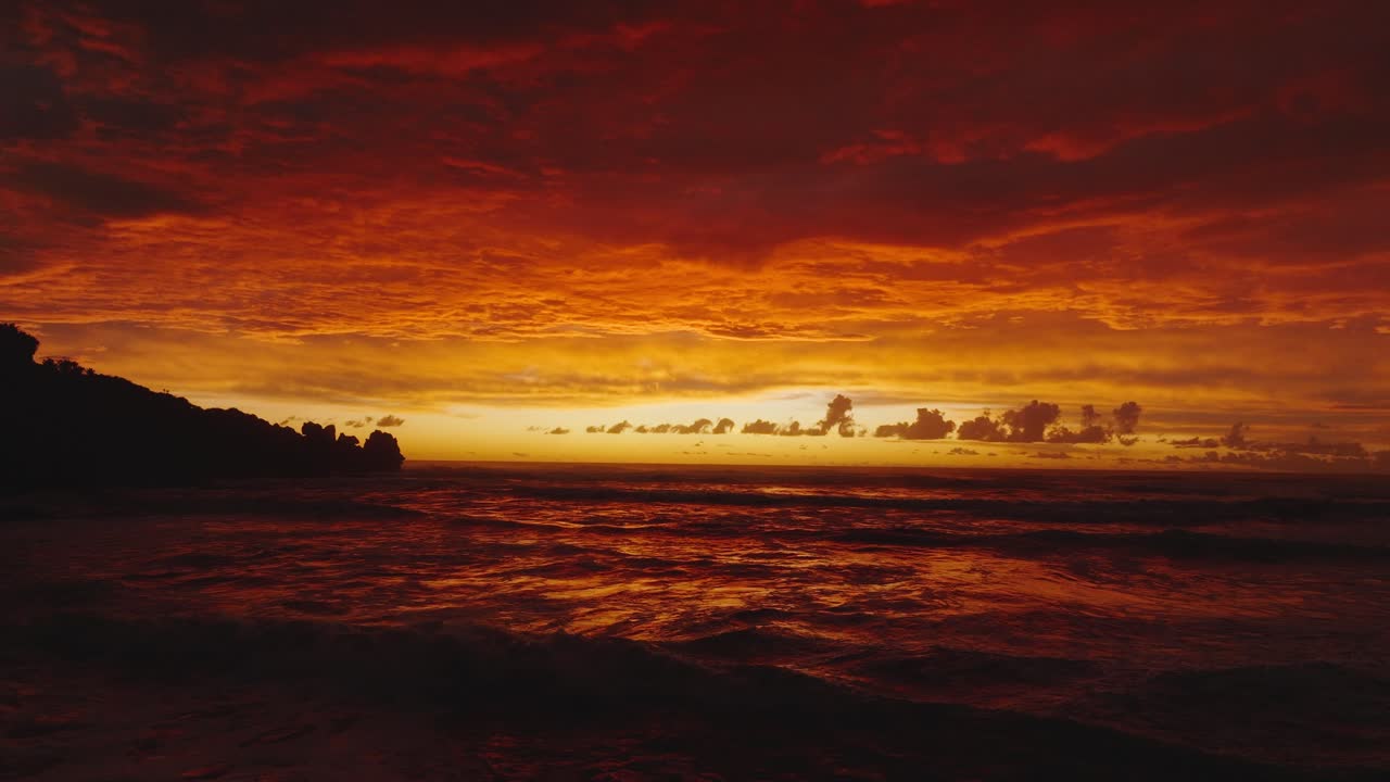 Slow motion aerial seascape view of golden orange and red sunset and Tasman Sea with rolling waves on the West Coast of South Island in New Zealand Aotearoa