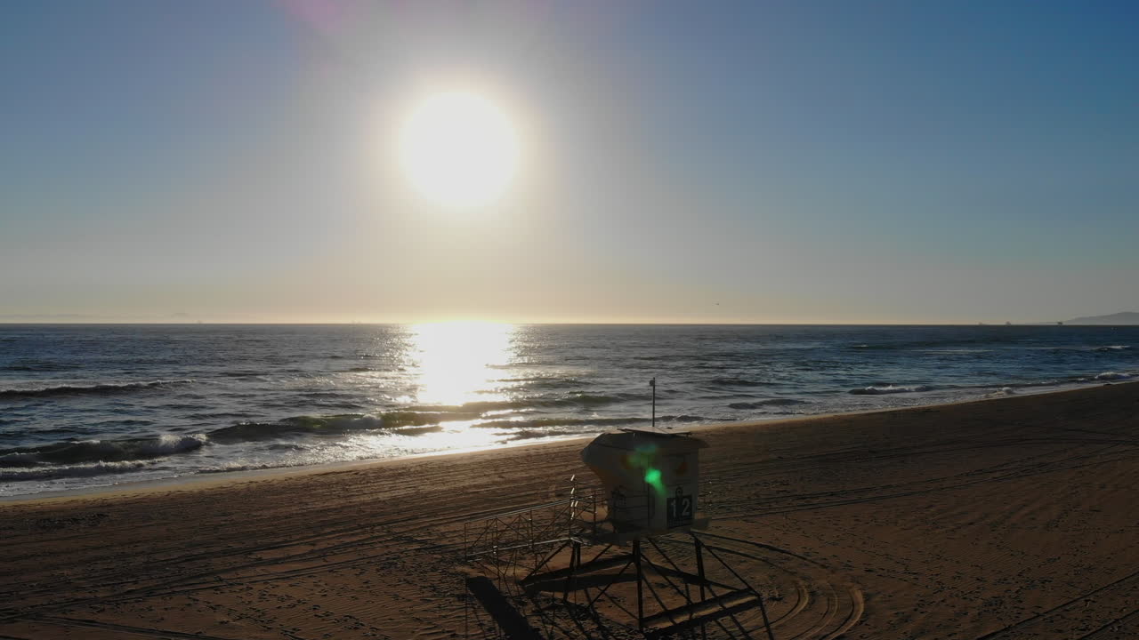 인명 구조원 타워는 캘리포니아 헌팅턴 비치에서 공중 4k 드론으로 아름다운 바다 일몰과 파도를 향해 날아갑니다.