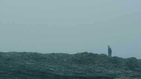 Man-hiking-near-cliffs-on-a-foggy-day