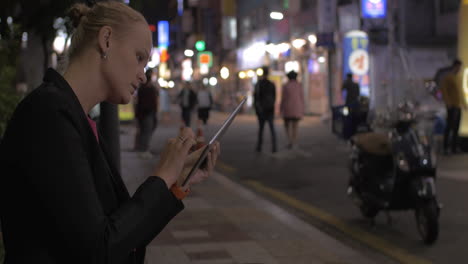 Mujer-Trabajando-Con-Pad-En-La-Calle-Nocturna-De-Seúl,-Corea-Del-Sur