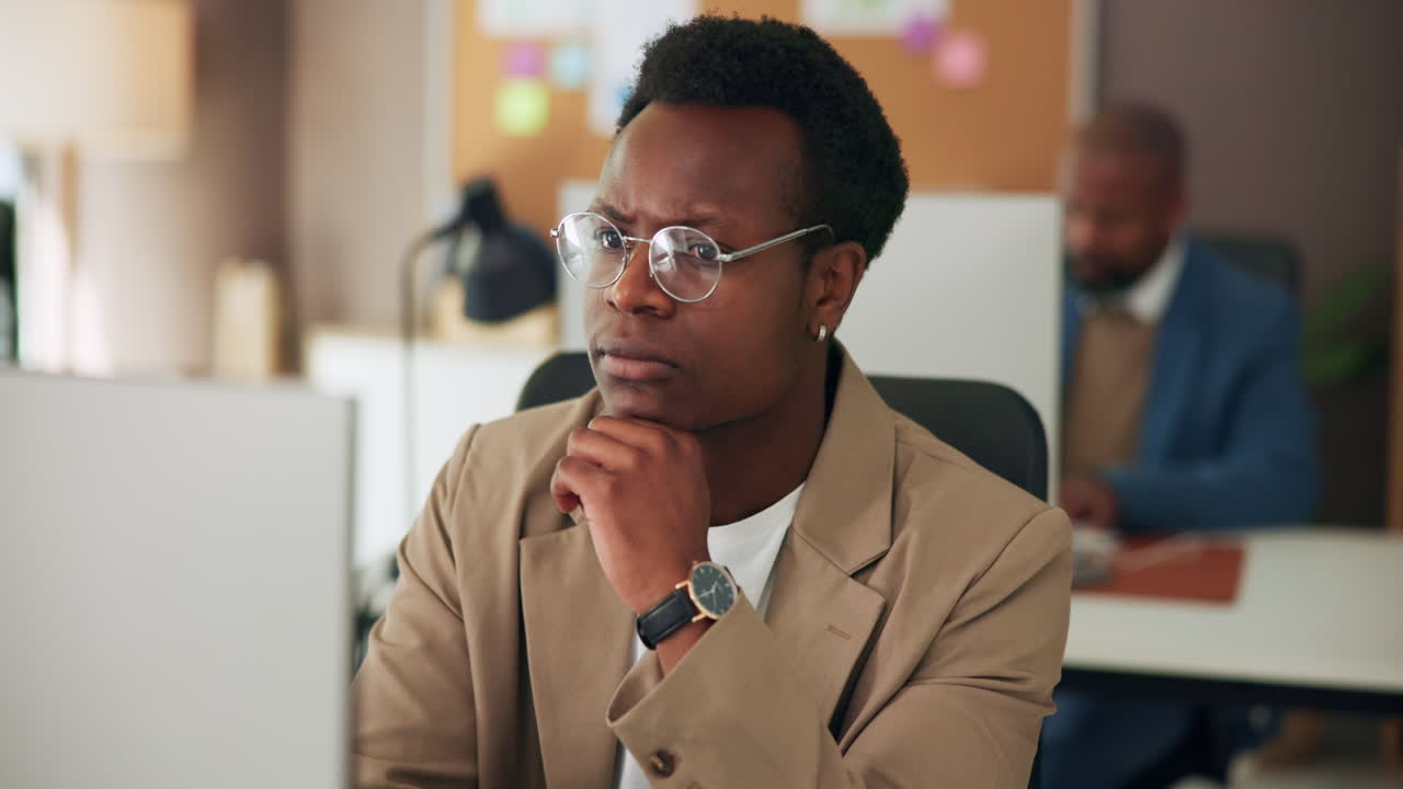 Young African American Man Working and Thinking in Modern Office