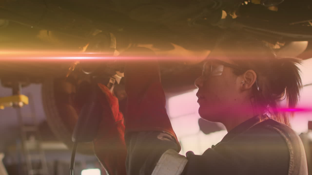 animación de luz brillante sobre una mujer biracial que trabaja en un taller de automóviles