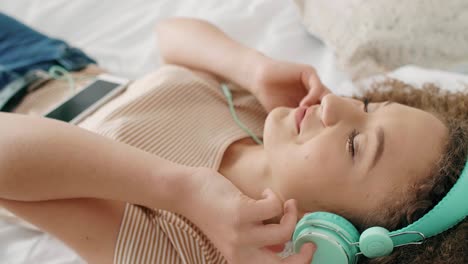 smiling woman listening to music and relaxing on the bed