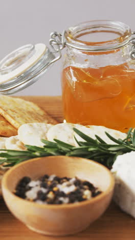 bowl of green olives, spices, crispy biscuits, jam, rosemary herb, cheese and walnuts