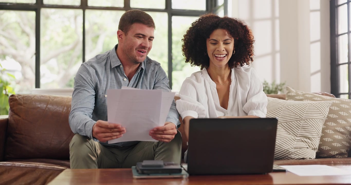 Happy Couple Reviewing Documents Together on Laptop at Home
