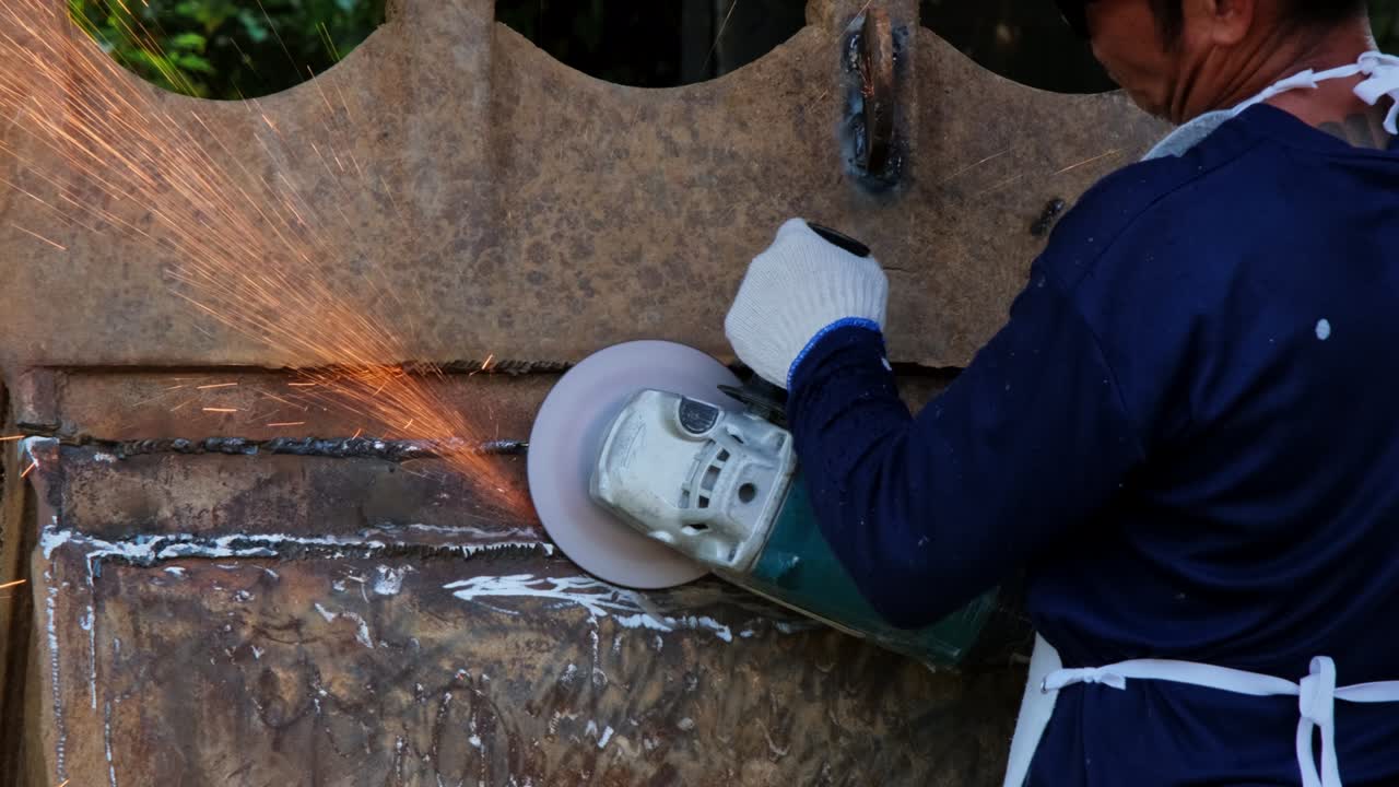 hombres profesionales que usan gafas de protección y guantes de construcción trabajan en el taller de casa con un molinillo angular. el metal de lijado hace chispas, primer plano