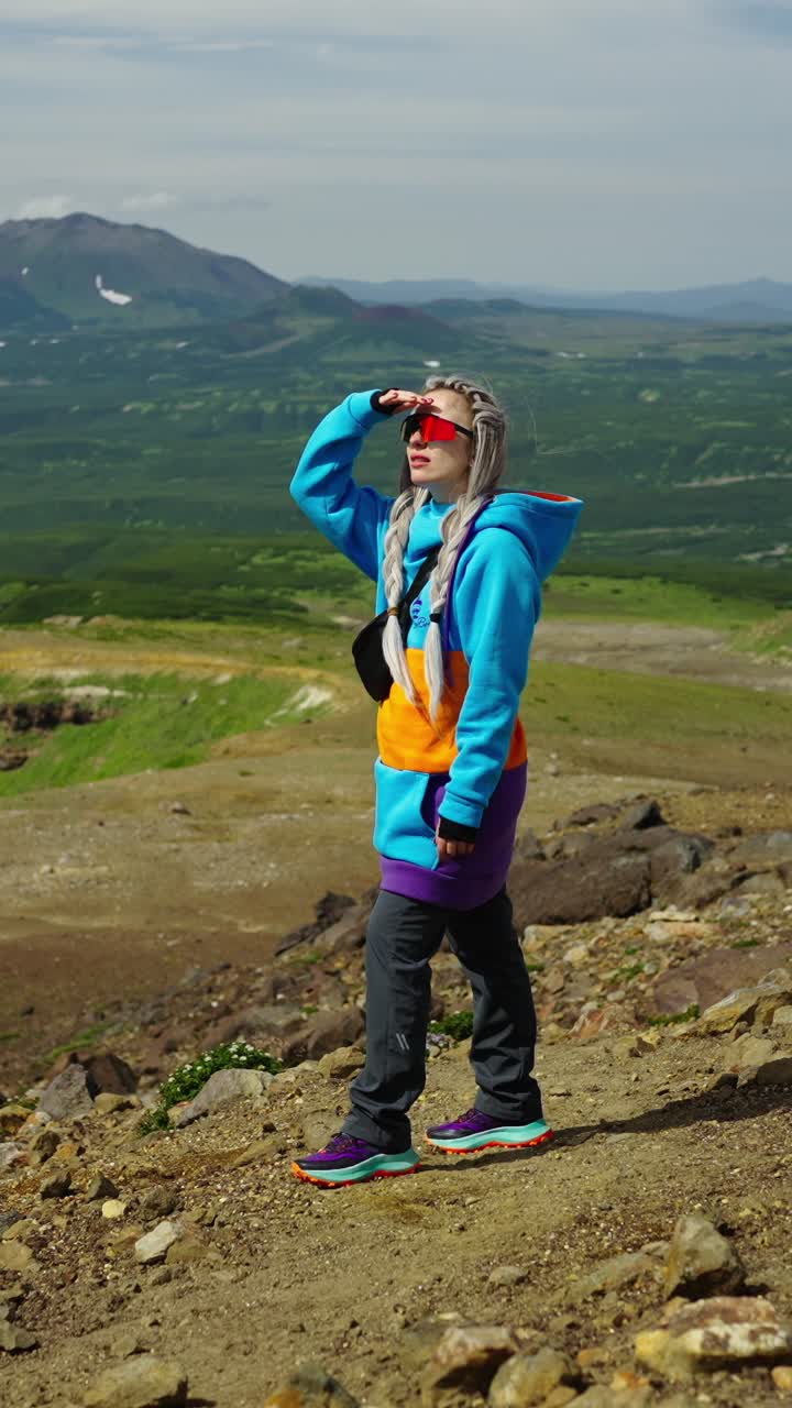 Donna in piedi sulla cima di una montagna che ammira un vasto paesaggio