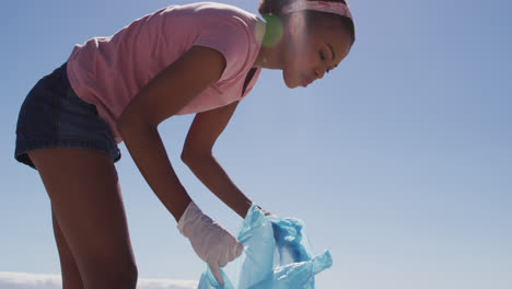 african american woman collecting plastic waste on the beach