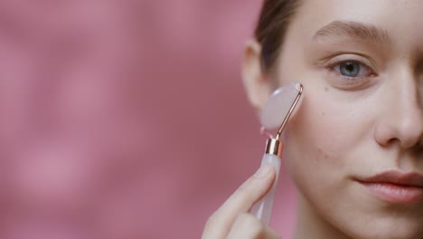 mujer usando un rodillo de jade para el masaje facial