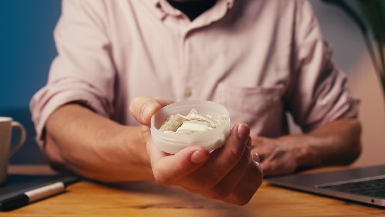 Snus nikotintobak tæt på, pakke snus. Usund afhængighed. Mand åbner æske med snus og tager en.