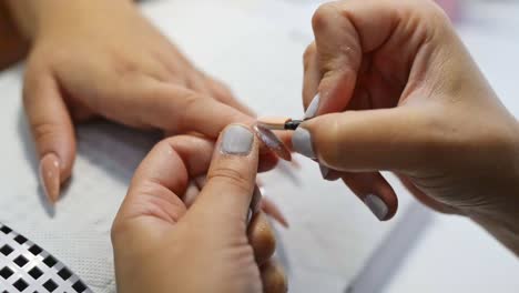 Artista-De-Uñas-Aplicando-Esmalte-Brillante-En-El-Salón