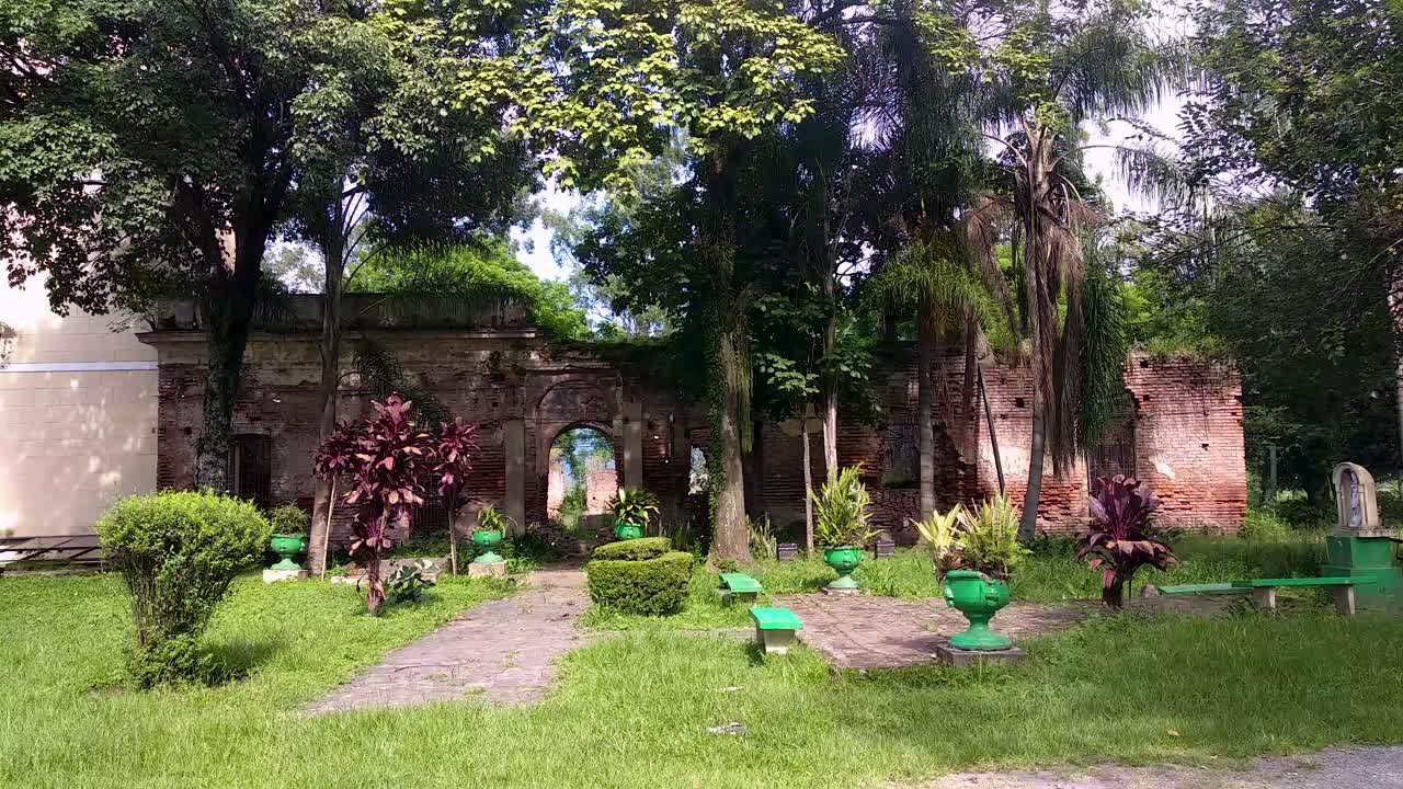 Pengambilan gambar pan melintasi seorang wanita yang memotret taman di Misión Jesuitica San José de Lules