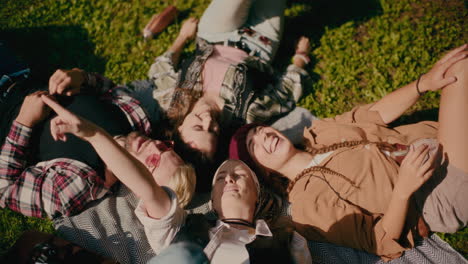 cheerful friends having fun while lying down at park