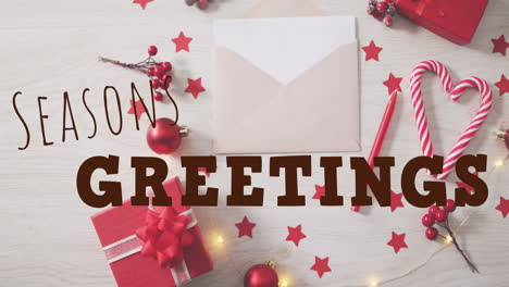 animation of seasons greetings with stars, sticks, gift boxes and envelope over white background