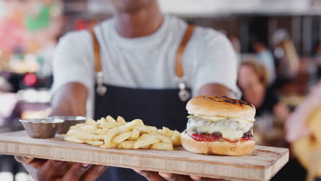 Nahaufnahme-Eines-Kellners,-Der-In-Einem-Belebten-Barrestaurant-Burger-Und-Pommes-Frites-Serviert