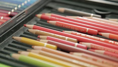 close-up of an artist's hand selecting colored pencils from a set, vibrant and detailed