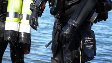 un buzo con su equipo totalmente negro sale del agua, primer plano de su equipo