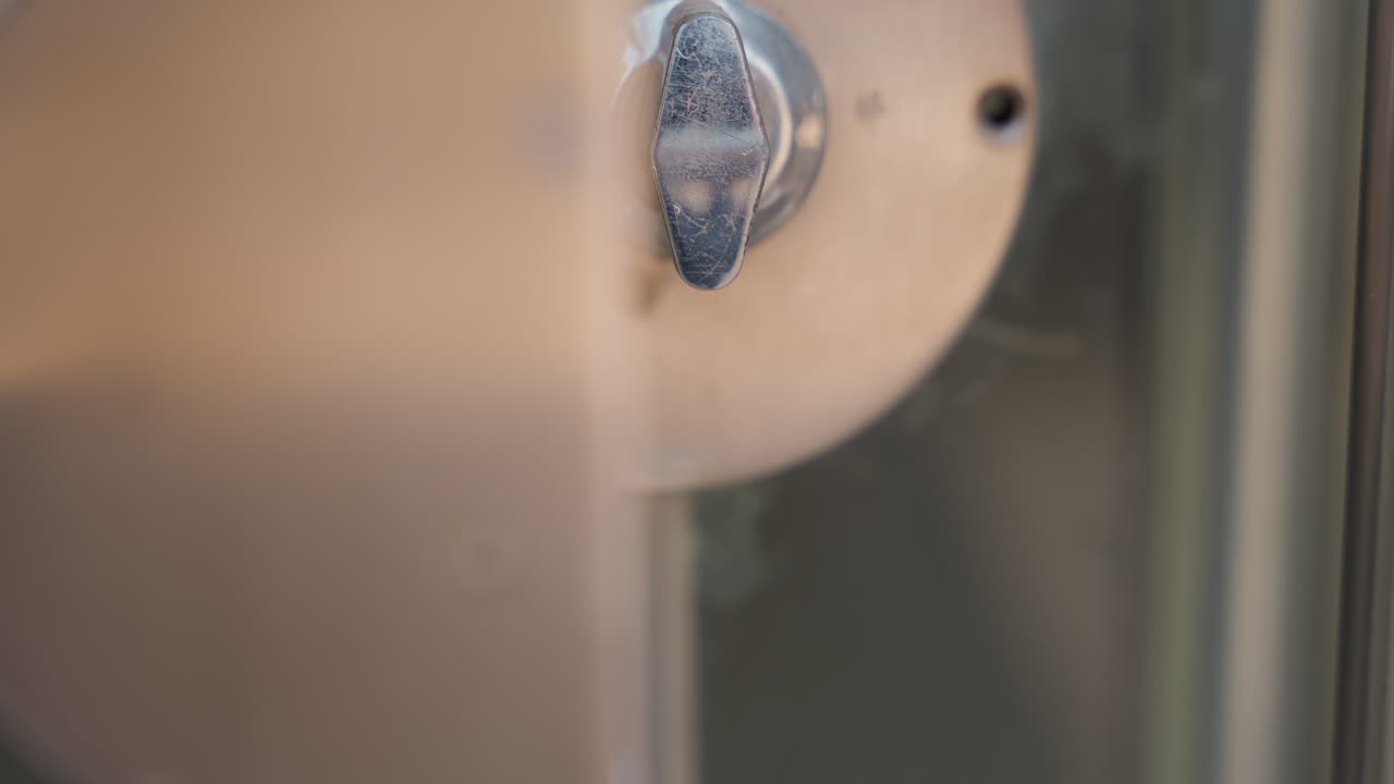 Video ravvicinato di una maniglia lucida che mostra una riparazione. La superficie metallica è stata levigata, con l'azione implicita di un tecnico che usa cacciavite e panno per la rimozione della corrosione e un restauro graduale. Illuminazione da studio neutra, a fuoco.