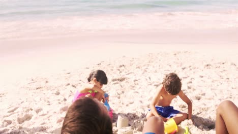 parents watching children building a sand castle