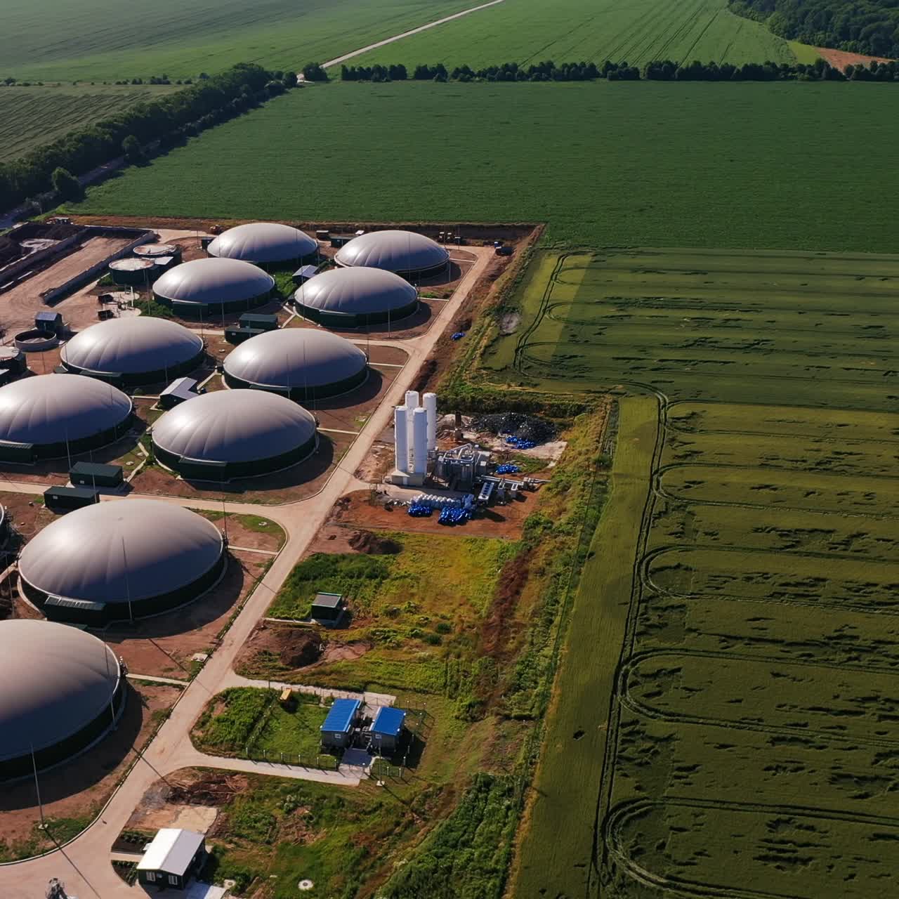 Round reservoirs of biofuel production factory. Tops of the biomass tanks shining in the sun against the nature background