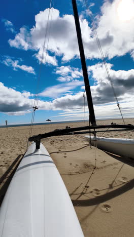 catamaran is anchored on a sandy beach, with their sails furled. on the background the sea. catamaran on the beach. in algarve, portugal.