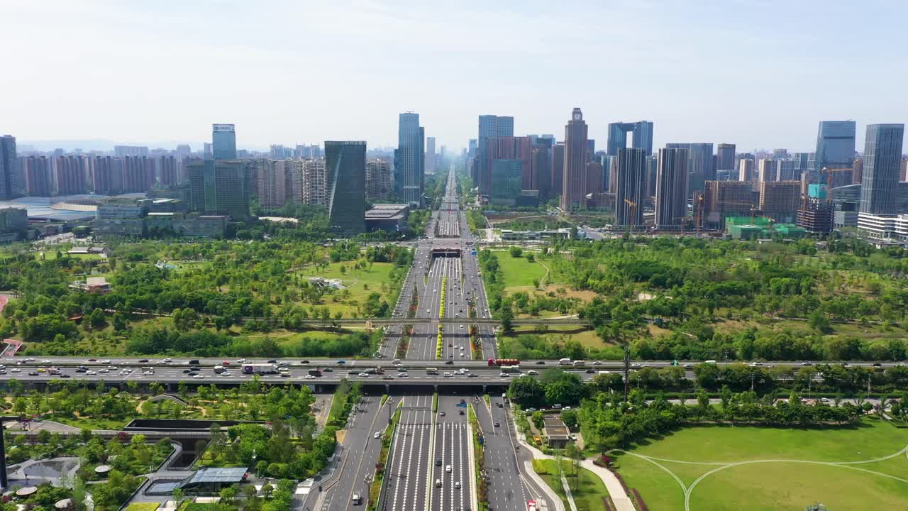 Aerial view of Tianfu New Area in Chengdu, China, showing symmetrical highways cutting through green urban parks, surrounded by dense modern skyscrapers under clear skies.